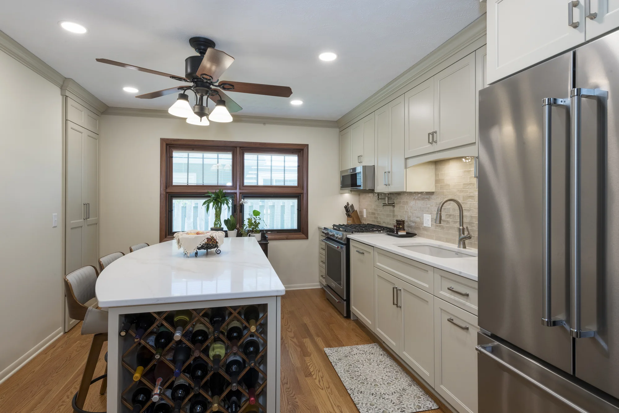 Curved island and warm neutral cabinetry viewed from the refrigerator wall