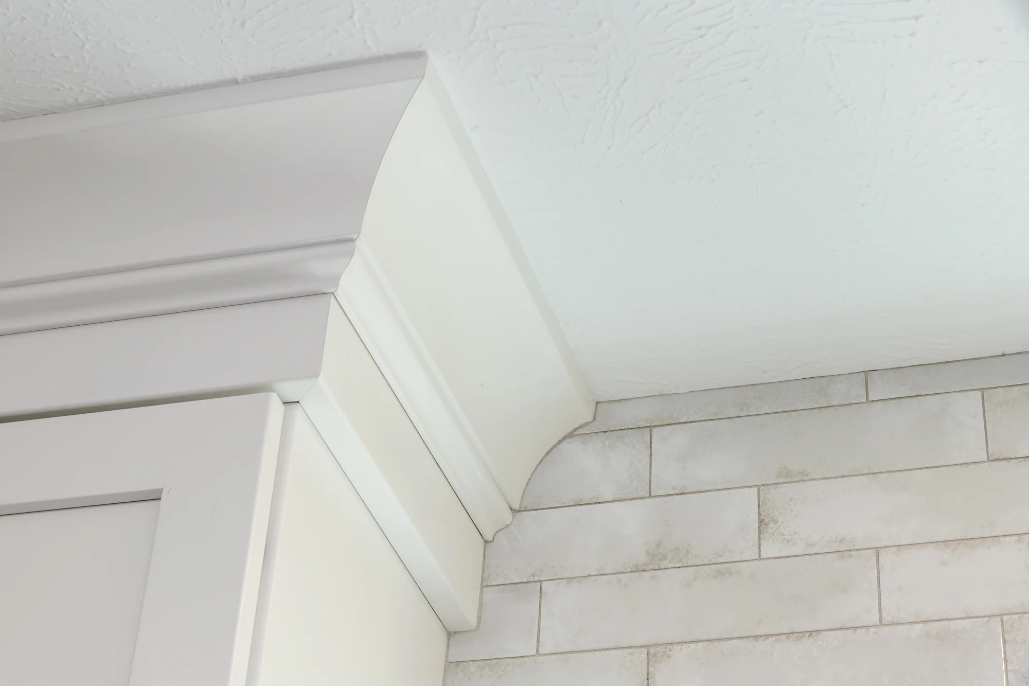 Crown molding and tile detail above the white cabinetry