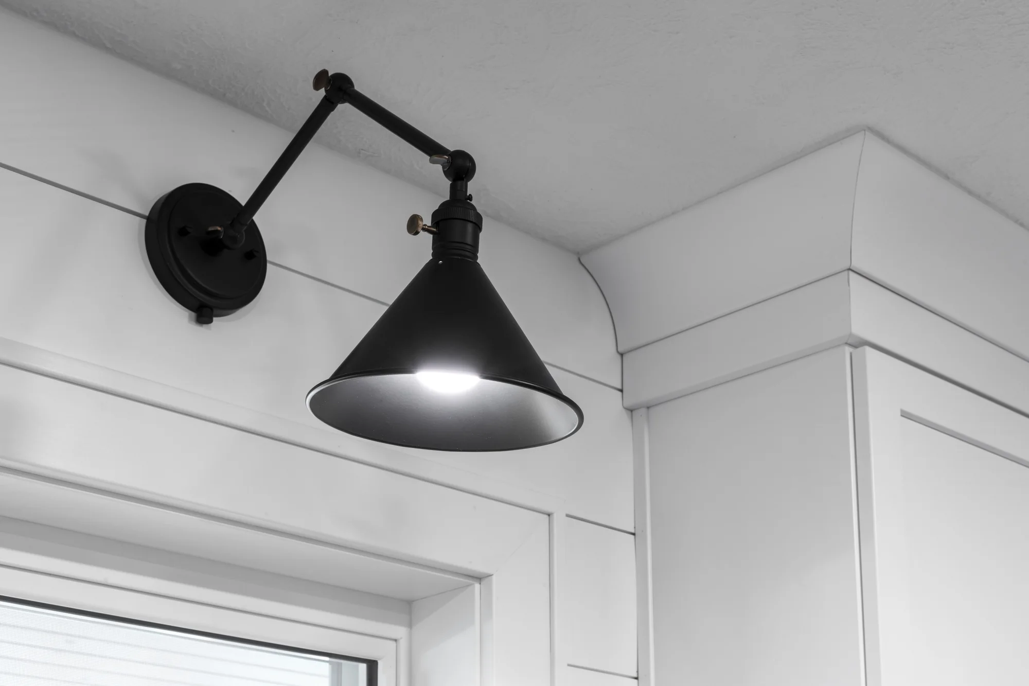 Black farmhouse-style wall light above white shiplap